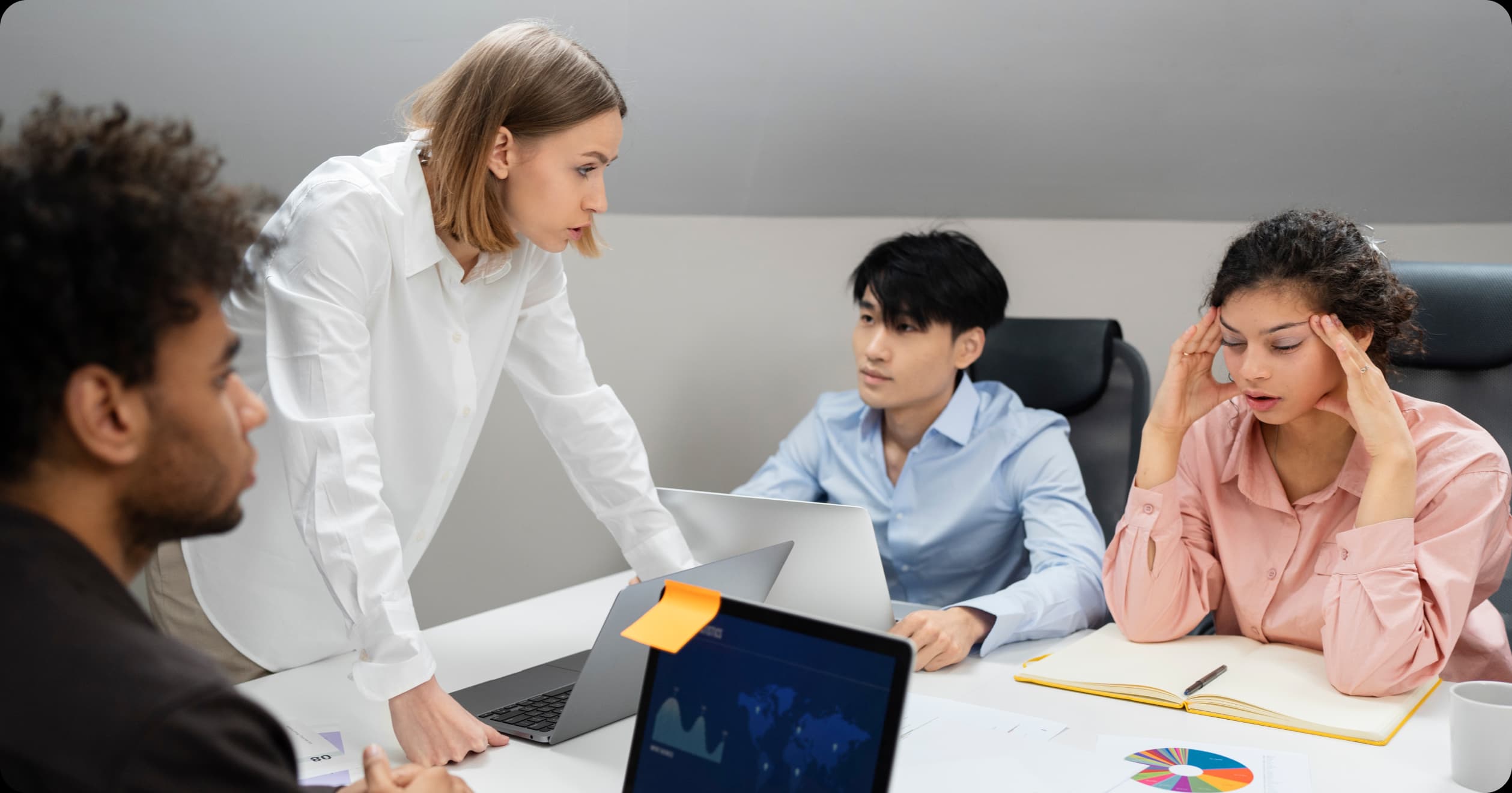 Employees in a corporate meeting showing signs of stress and burnout, highlighting the need for physician-led wellness strategies in the workplace.