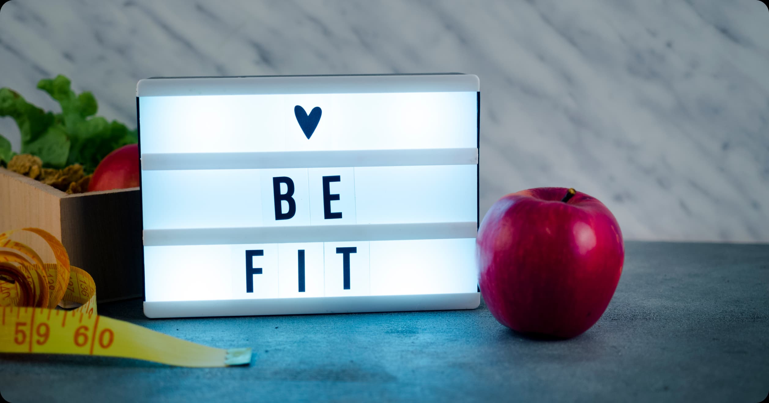 "Be Fit" sign with apple and measuring tape symbolizing healthy lifestyle and wellness choices for employees.