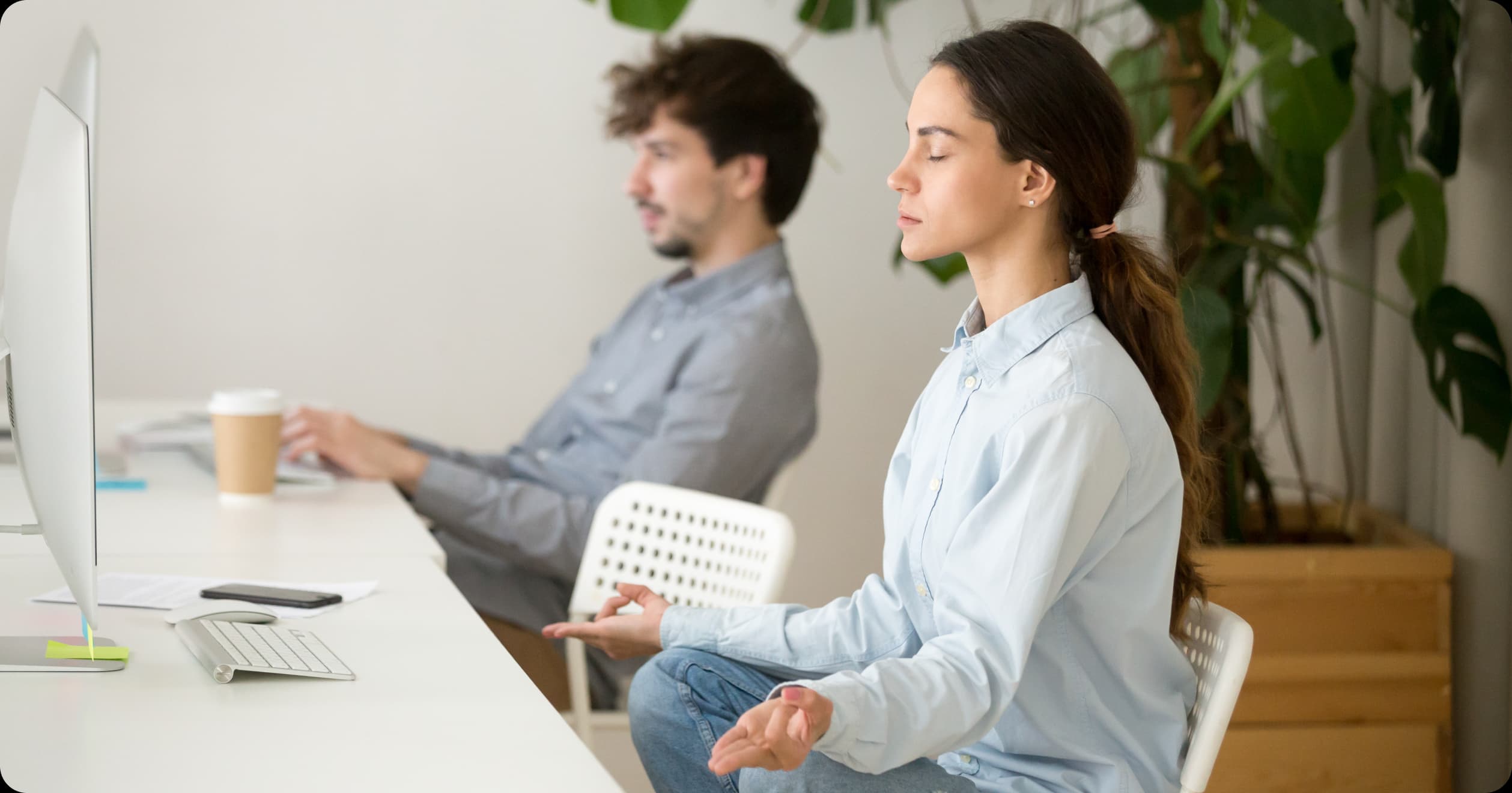 Woman meditating at desk in office, promoting brain health and stress reduction for workplace productivity.