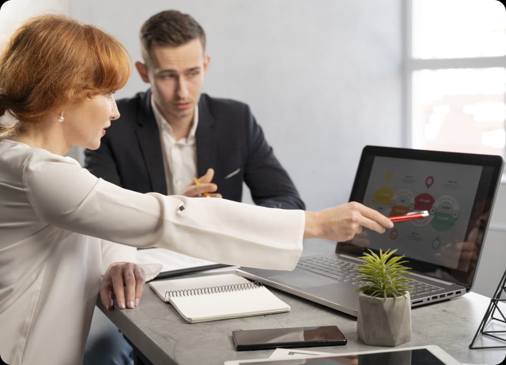Business professionals reviewing data on a laptop, symbolizing brokers guiding wellness programs for risk management.