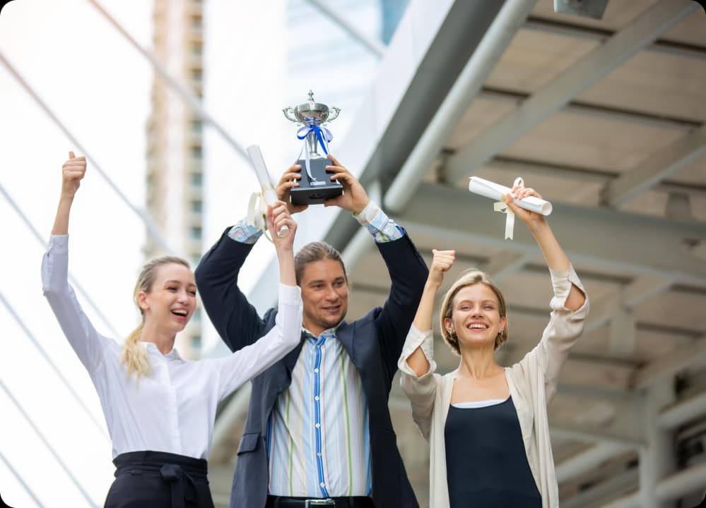 Happy employees celebrating with trophy and certificates, symbolizing the power of rewards and recognition in boosting wellness.