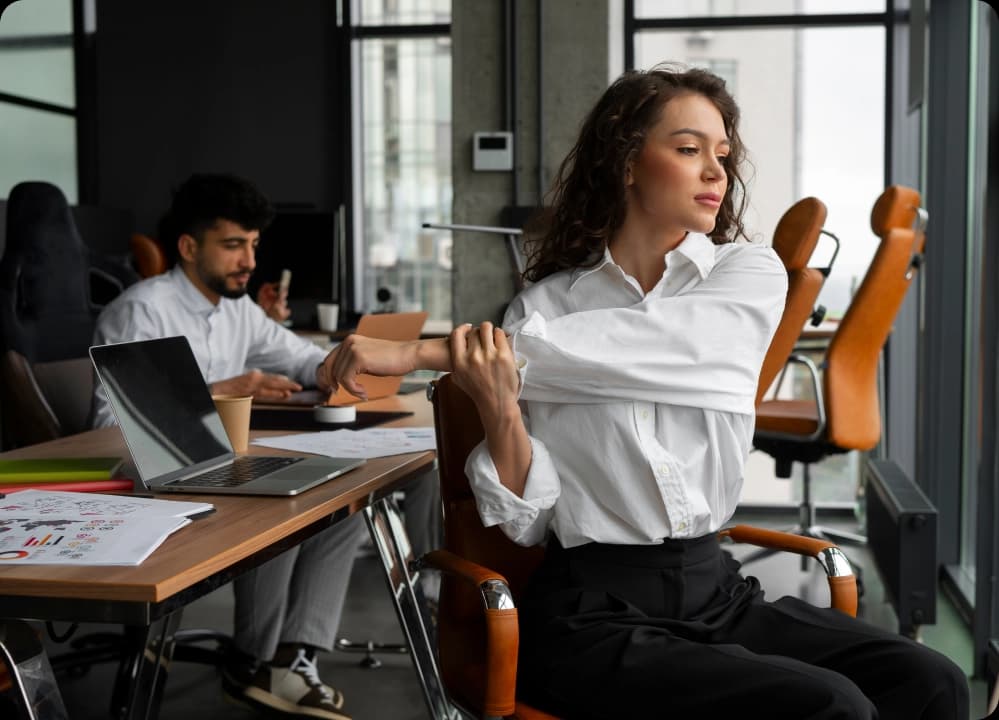 Woman stretching at desk in modern office as part of workplace stress relief routine