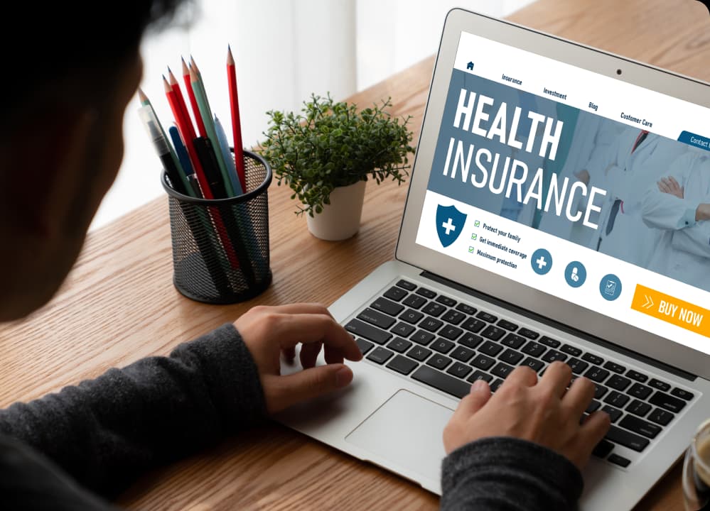 Man using laptop to explore health insurance options, highlighting digital wellness trends