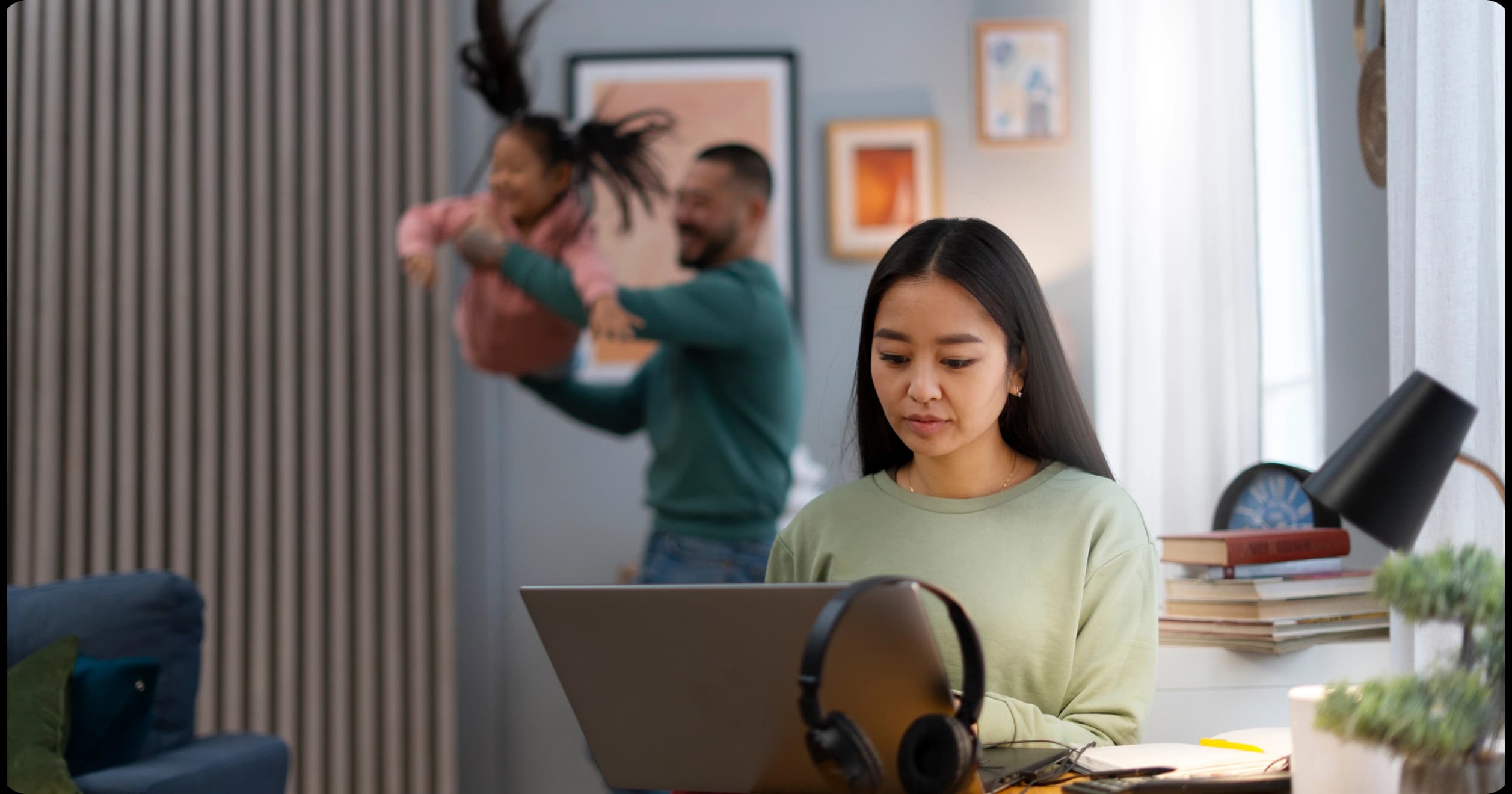 Woman working remotely while family plays in the background at home
