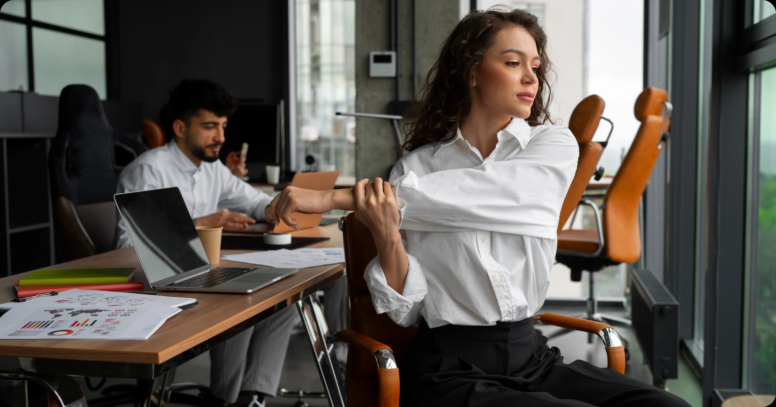 Woman stretching at desk in modern office as part of workplace stress relief routine