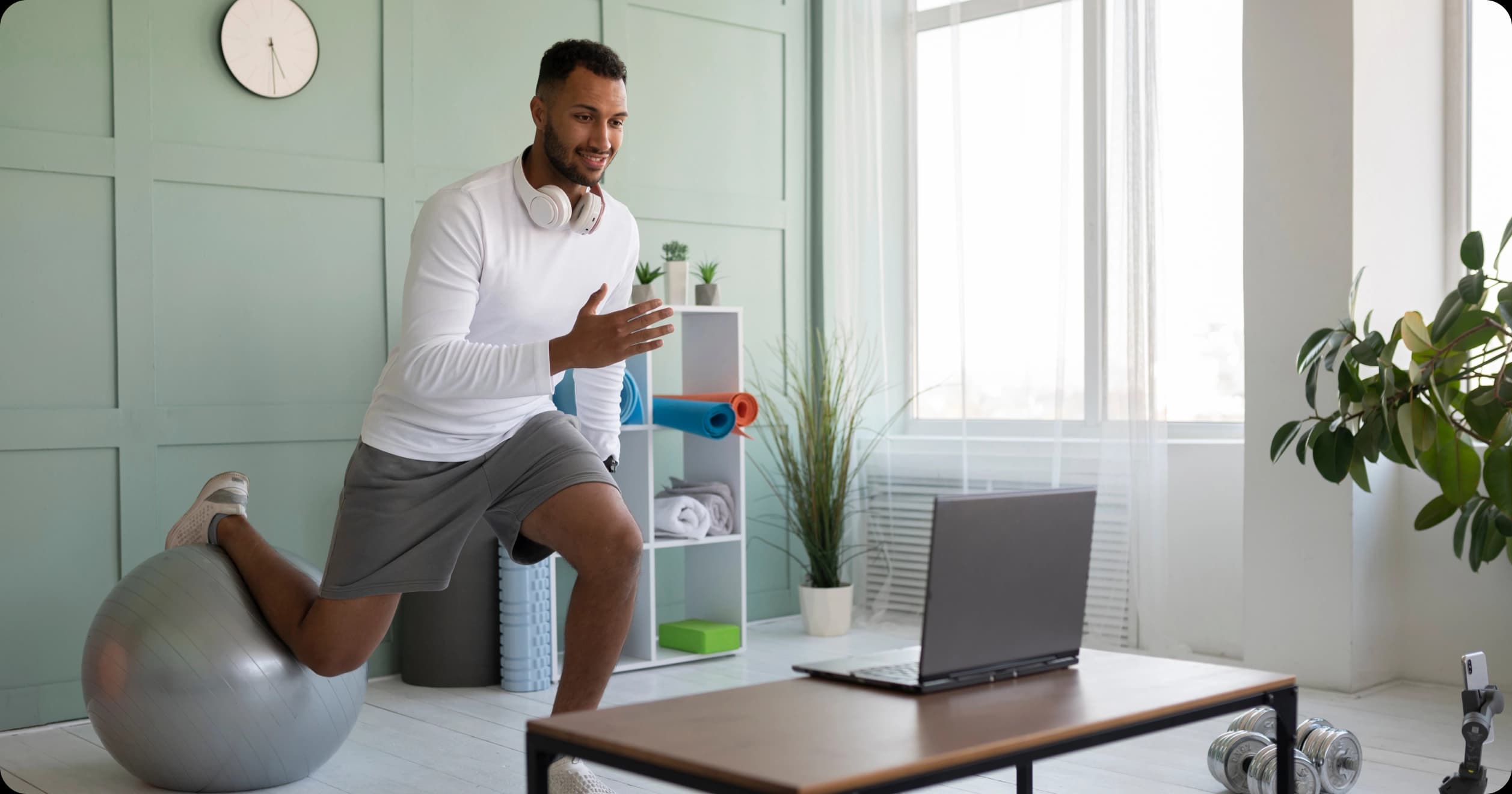 Man doing virtual workout on exercise ball during online fitness session at home