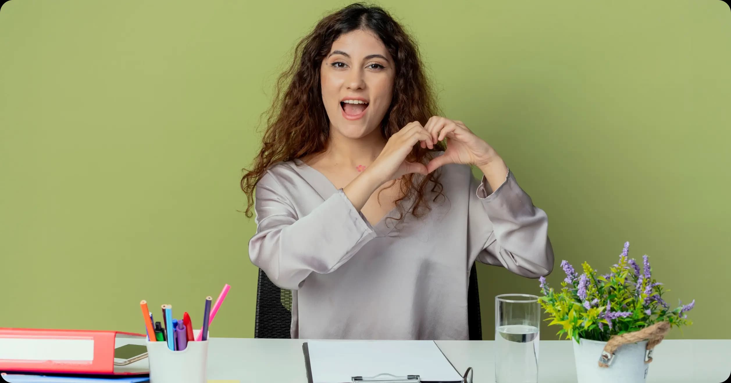 Smiling employee making a heart gesture with hands to promote positivity and workplace wellbeing